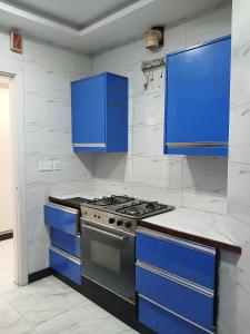 a kitchen with blue cabinets and a stove at Cottage Inn in Faisalabad