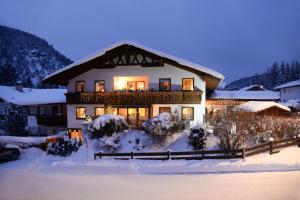 a house in the snow with lights on at Alpen Appartements Marlene in Ehrwald