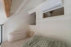 a white room with a bed and a chair at L'hôtel des oiseaux in Les Baux-de-Provence