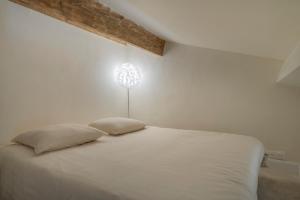a white bedroom with a bed with a light on the wall at L'hôtel des oiseaux in Les Baux-de-Provence +67 photos