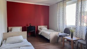 a room with two beds and a red wall at Apartament Ogrodowa in Muszyna