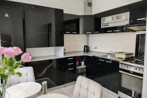 a black and white kitchen with a vase of pink flowers at Apartament Ogrodowa in Muszyna