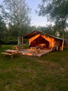 a wooden cabin with picnic tables in front of it at Natur'O Médoc in Naujac-sur-Mer