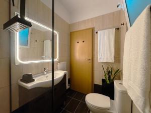 a bathroom with a sink and a toilet and a mirror at Whitealcyone Fit & Zen Apartment in Artemida