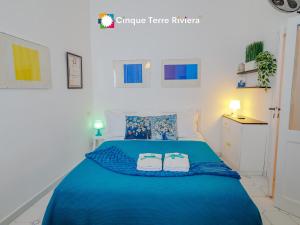 a bedroom with a blue bed with two towels at Maemuna Sea View Apartment in Vernazza