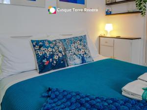 a bed with blue sheets and pillows on it at Maemuna Sea View Apartment in Vernazza