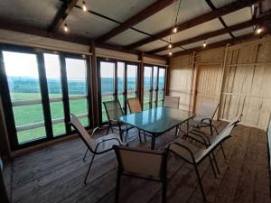 a dining room with a table and chairs in a room with windows at Kowolove in Bańska Wyżna