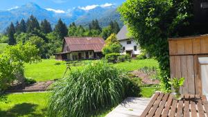 a house in a field with mountains in the background at Fresh romance by the river in Bohinj