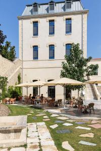 a building with tables and umbrellas in front of it at Hôtel du Parc in Arles