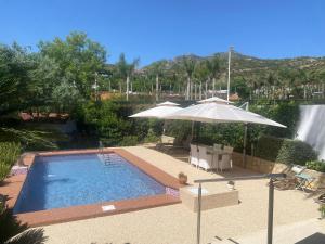 a swimming pool with an umbrella and a waterfall at Berg & Zon Private & Pet frendly in Gandía