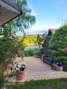 a patio with a bench and a lake in the background at Mała Garda in Brodnica Dolna