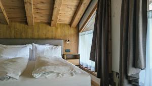 a bed with white sheets and pillows in a bedroom at Tilio Chalet in Livigno