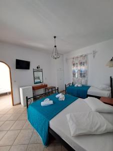a hotel room with two beds and a desk at Hotel Posidonion in Koufonisia