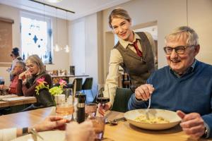 a woman standing over a man eating food at a table at Das Mühlentor Hotel mit Restaurant - moderne Zimmer - leckere Heimatküche - familiär geführt in Bad Kreuznach