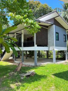 a white house with a tree in front of it at Jungle Hideaway with Pool Wifi Smart TV in Ban Tai