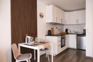 a kitchen with white cabinets and a table and chairs at Albview-Apartment1 -zentral-Nähe Klinik-Therme-Agilent in Waldbronn
