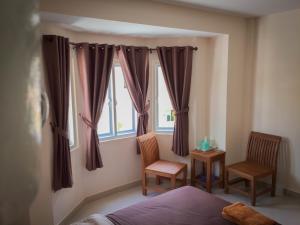 a bedroom with a bed and two chairs and a window at Romruedee Resort in Sattahip