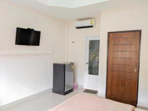 a room with a refrigerator and a television on the wall at Romruedee Resort in Sattahip
