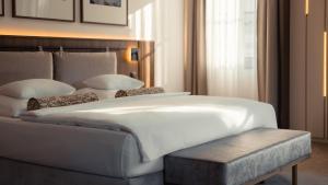 a bedroom with a large white bed and a bench at Hotel Savoy Špindlerův Mlýn in Špindlerův Mlýn