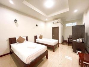 a bedroom with two beds and a table in it at janwareeresort in Sangkhla Buri
