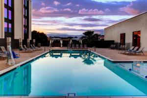 a swimming pool with chairs and a building at Doubletree by Hilton Arlington DFW South in Arlington