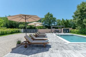 a group of lounge chairs and an umbrella next to a pool at Villa Ardanela in Labin