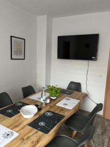 a wooden table with chairs and a television on a wall at Ferienwohnung Krayenbergblick 2 in Tiefenort +2 photos