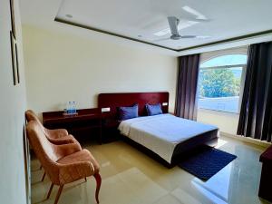a bedroom with a bed and a chair and a window at Kamaksha Palace in Sundarnagar +23 photos