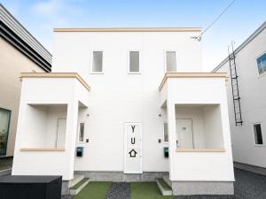 a white house with two garage doors at 優富良野 in Furano