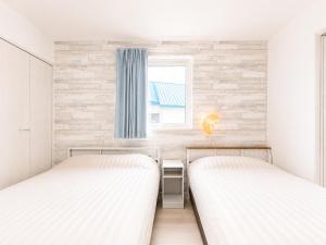 two beds in a small room with a window at 優富良野 in Furano