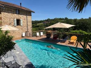 a person swimming in a swimming pool next to a house at Chambres D'hôtes du Pentadou in Felzins