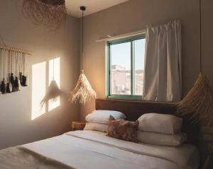 a bedroom with a bed with white sheets and a window at Amara Travel in Zuqim