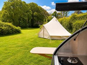a white tent sitting in the grass next to a car at Glamping Privé 2 tentes pour vous sur le mont à Tilff in Esneux