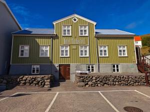 a large green building with a stone wall at Hótel Tindastóll in Sauðárkrókur