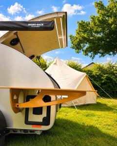 a white tent with a surfboard on the back of it at Glamping Privé 2 tentes pour vous sur le mont à Tilff in Esneux +2 photos