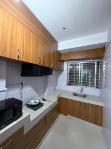 a kitchen with wooden cabinets and a sink and a microwave at Havene 11 in Dhaka