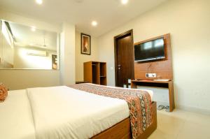 a bedroom with a bed and a desk and a television at Hotel Jullundur 18 in Chandīgarh