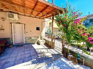 a porch of a house with a door and flowers at Olea Central Stay in Nea Kallikrateia