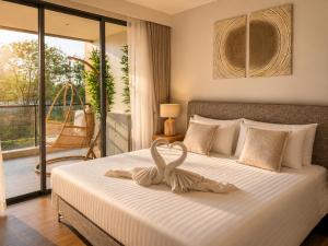 a bedroom with a large white bed with a balcony at Laguna Seaside 3 bed #84195 in Bang Tao Beach +24 photos