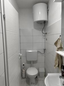 a white bathroom with a toilet and a sink at Rooms Lepara in Konjic