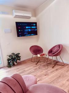 a living room with two chairs and a tv on the wall at Suite in Centro in Vasto