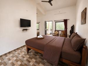 a bedroom with a bed and a flat screen tv at Vinsons Cottages in Colva