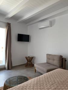 a bedroom with a bed and a couch and a television at Blue Paradise Apartments in Naxos Chora