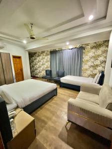 a hotel room with two beds and a couch at Emerald Inn in Islamabad