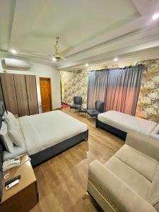 a hotel room with two beds and a couch at Emerald Inn in Islamabad
