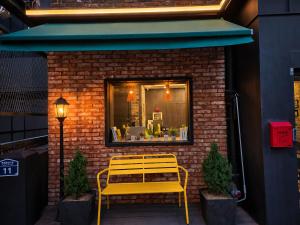 a yellow bench sitting in front of a store window at SR Compact Hotel Sinchon in Seoul