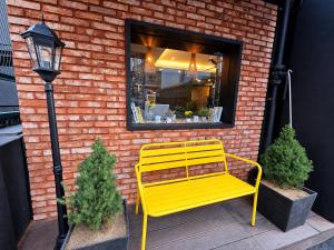 a yellow bench sitting in front of a brick building at SR Compact Hotel Sinchon in Seoul