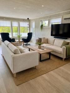 a living room with two couches and a flat screen tv at Willes Wellness Paradise in Herjenes