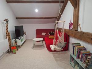 a living room with a red couch and a hammock at La maison COP&CO in Murat-sur-Vèbre