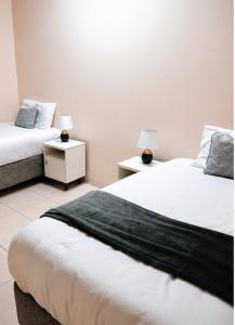 two beds in a room with two lamps on tables at The Vine House in Harare